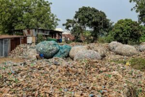 Outdoor view of a large pile of plastic waste and bottles in a recycling yard.
